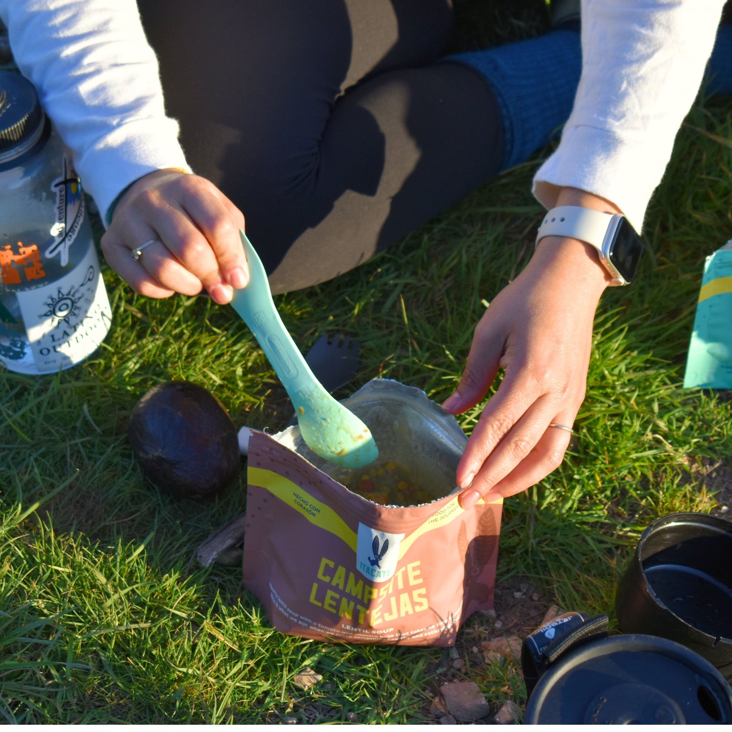 
                  
                    campsite lentils rehydrated in pouch, hiker using a green spoon to mix or scoop up meal
                  
                